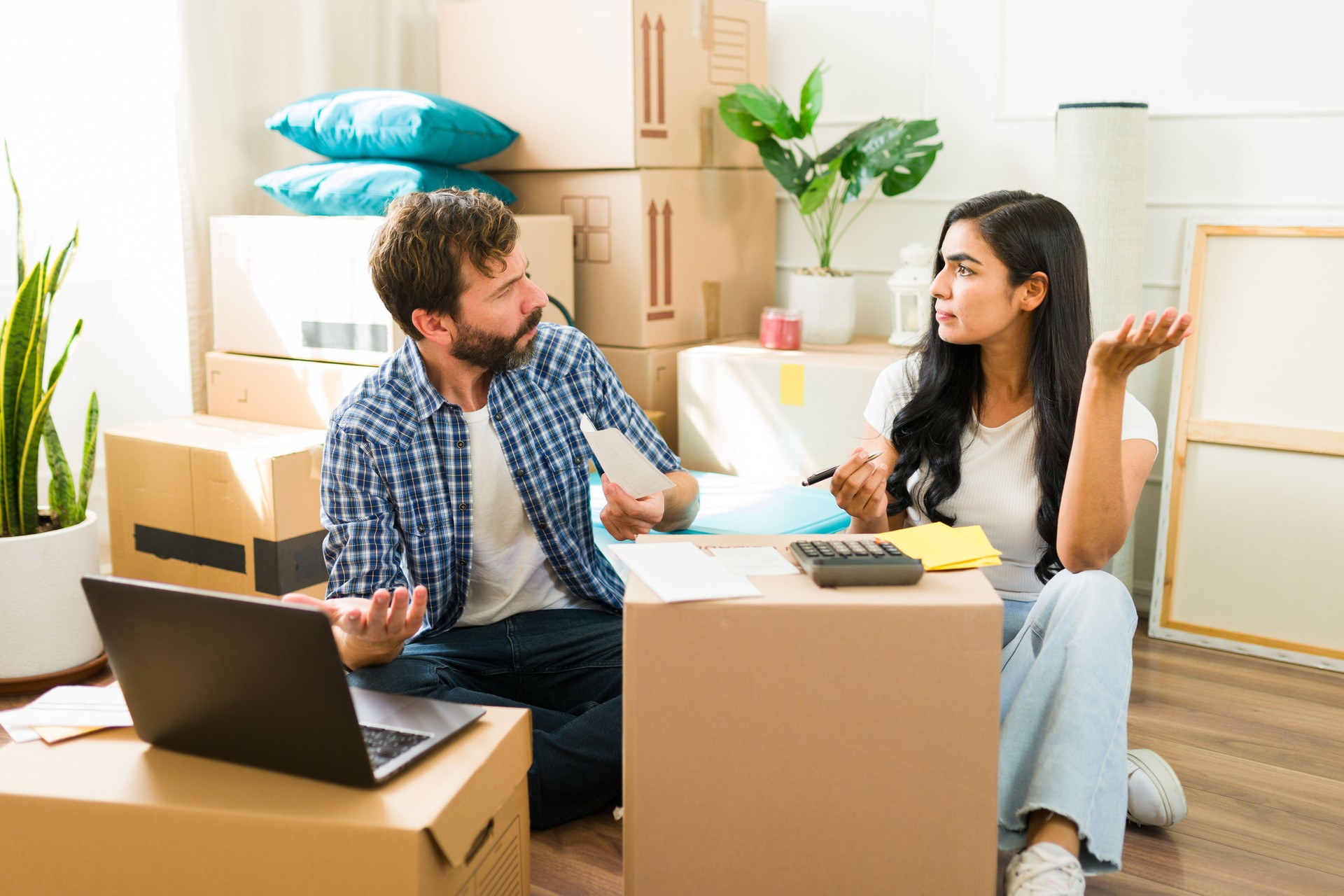 Disagreement over finances: young couple surrounded by moving boxes while sitting on the floor