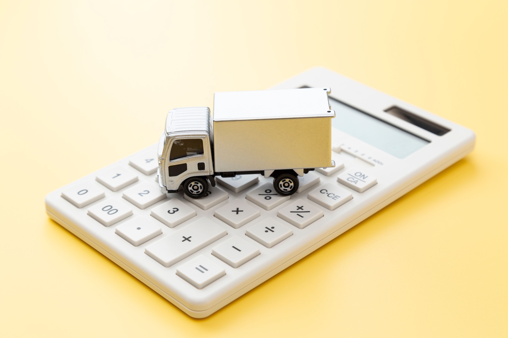 Truck and calculator on a yellow background.