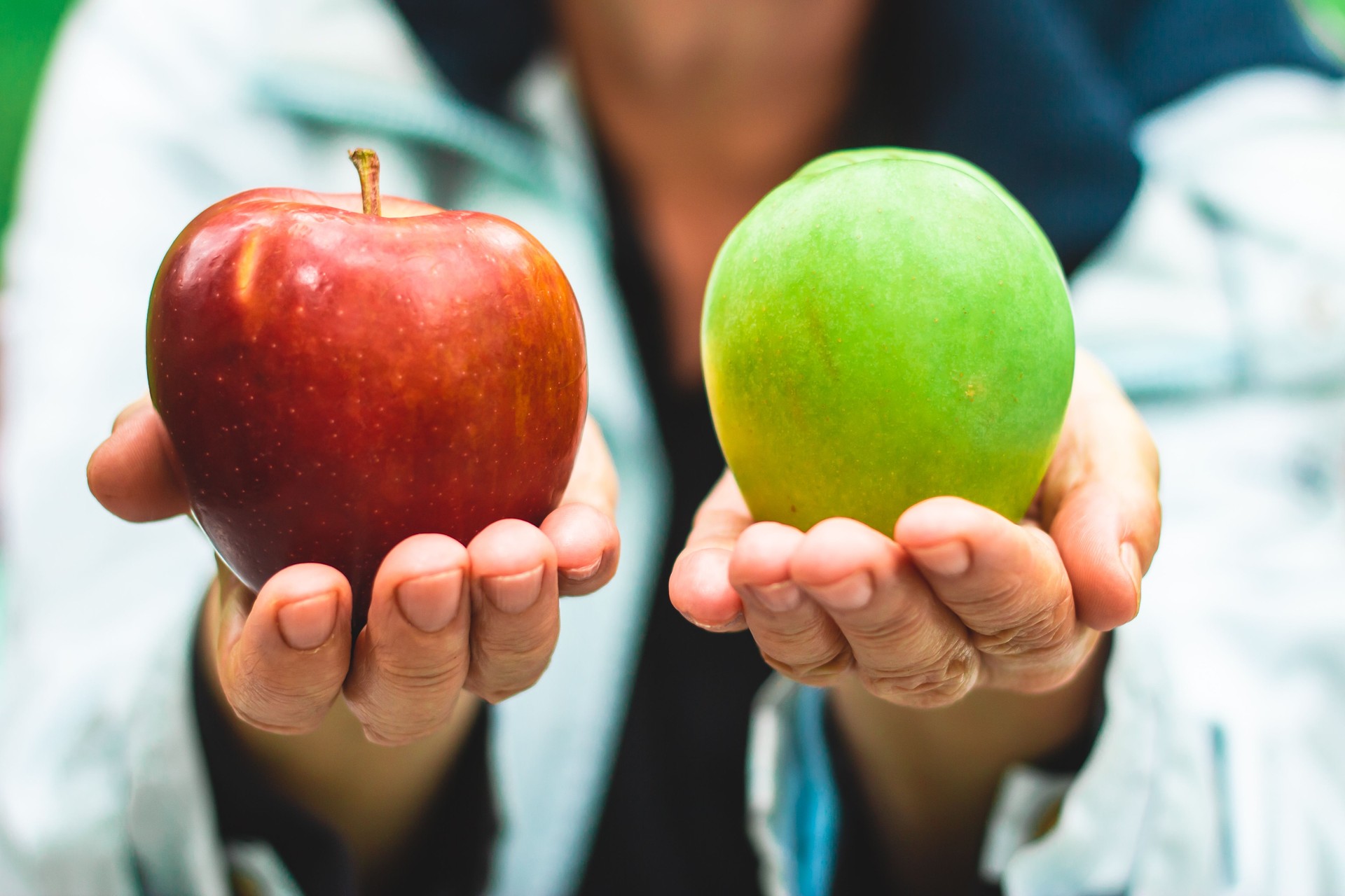 Closeup shot of mature hands holding a red and green apple