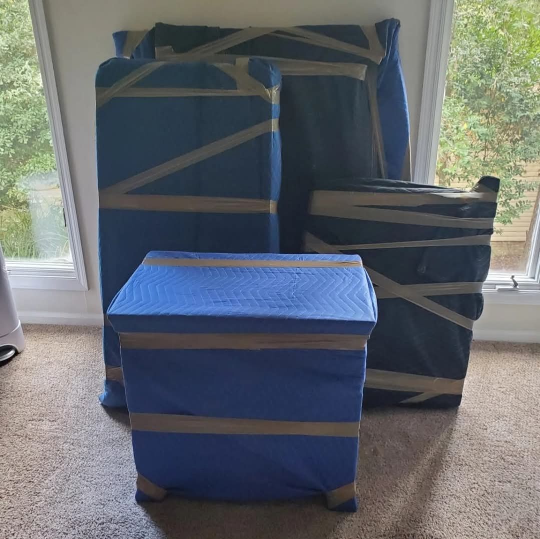 Large furniture pieces wrapped in blue moving blankets inside a home before transport — Dallas–Fort Worth