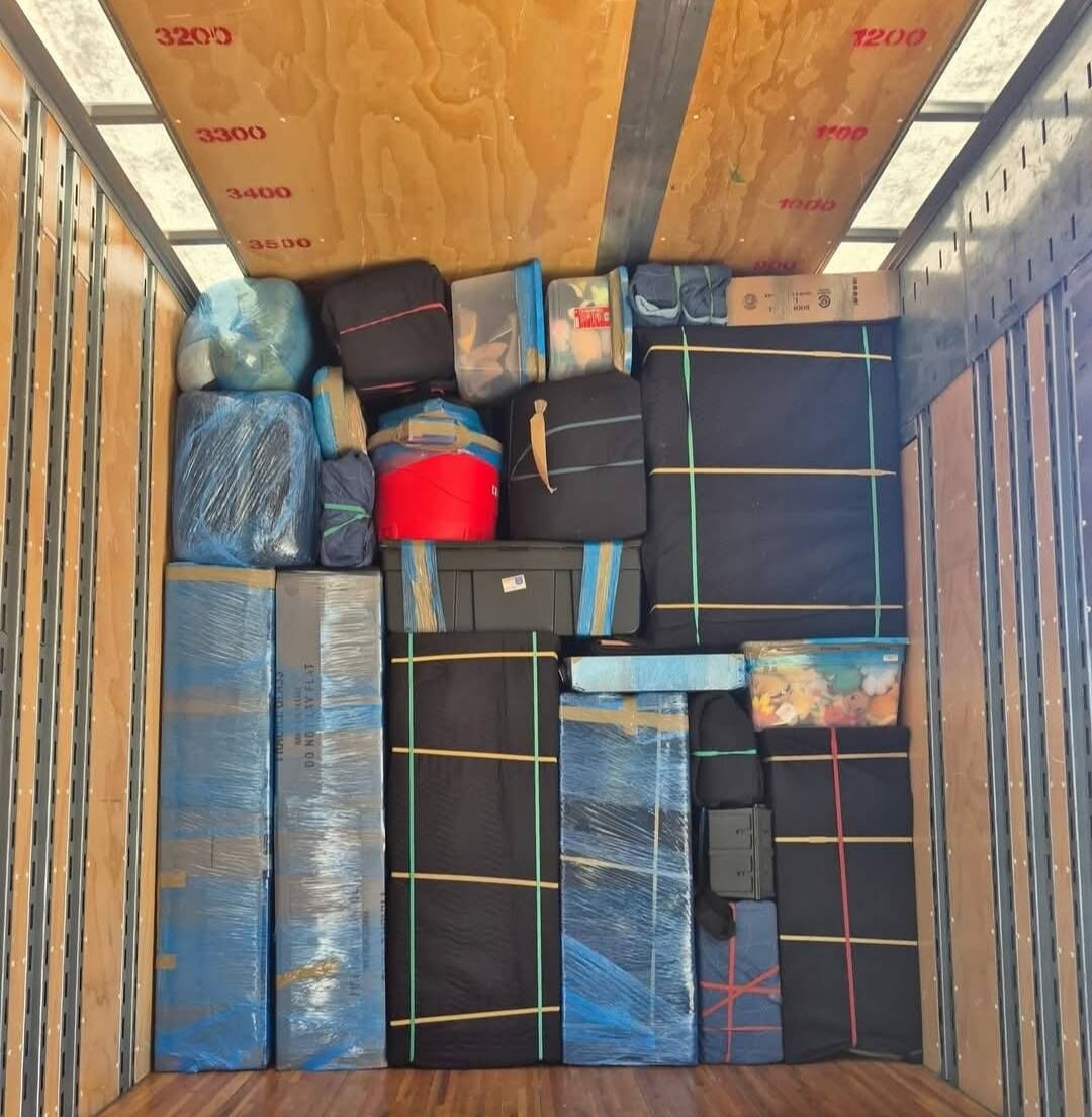 Aerial view of moving truck interior showing blue plastic-wrapped furniture and strapped items — One World Van Lines Carrollton, TX