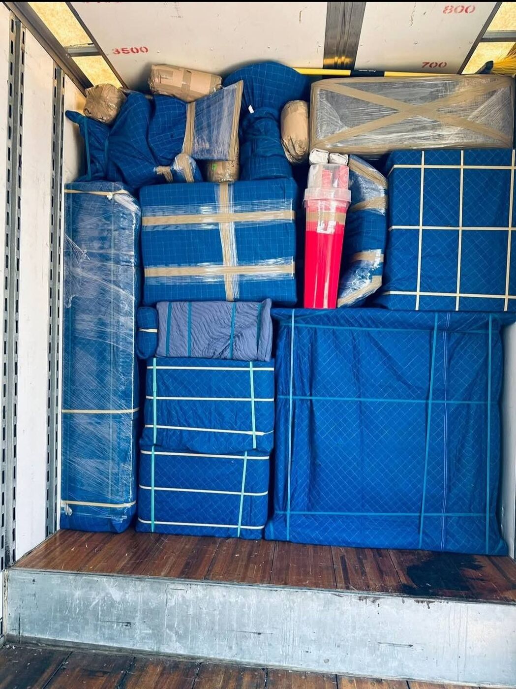 Blue moving blanket-wrapped furniture and mattresses tightly secured with straps in truck — One World Van Lines Dallas, TX