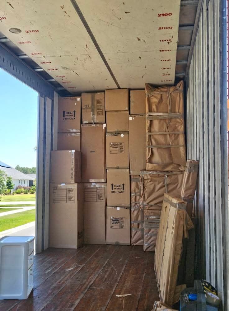 Dish-pack fragile boxes and kraft paper-wrapped specialty items loaded in moving truck at sunny suburban home — One World Van Lines Cedar Park, Greater Austin TX