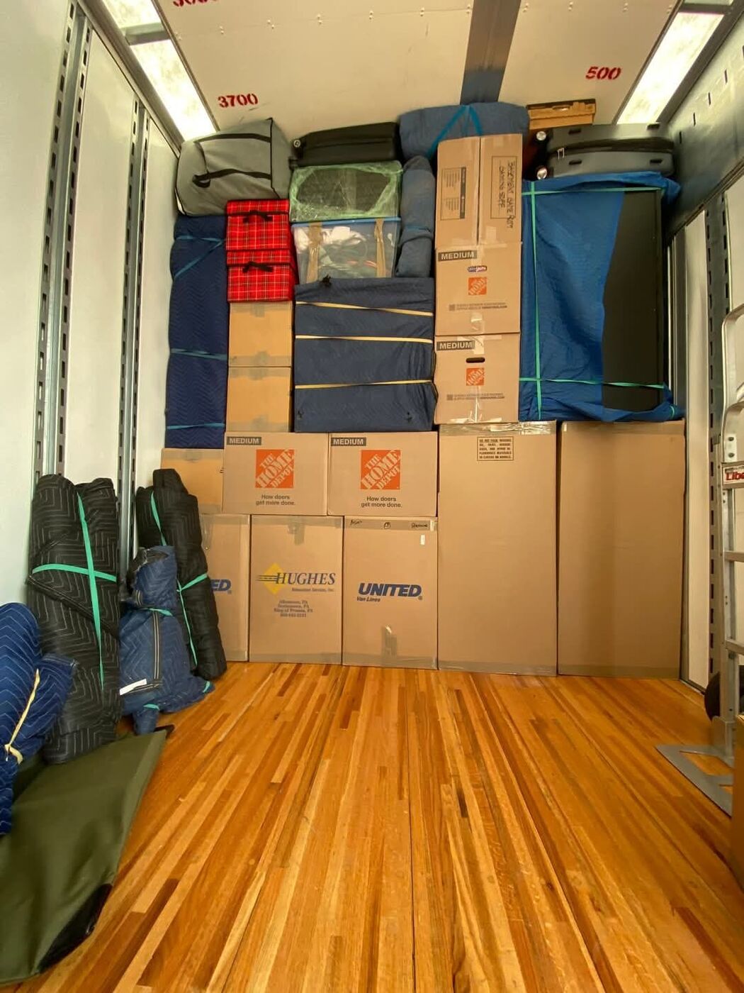 Mixed Home Depot boxes and blue moving blankets being loaded into moving truck — One World Van Lines Garland, TX DFW Metroplex movers