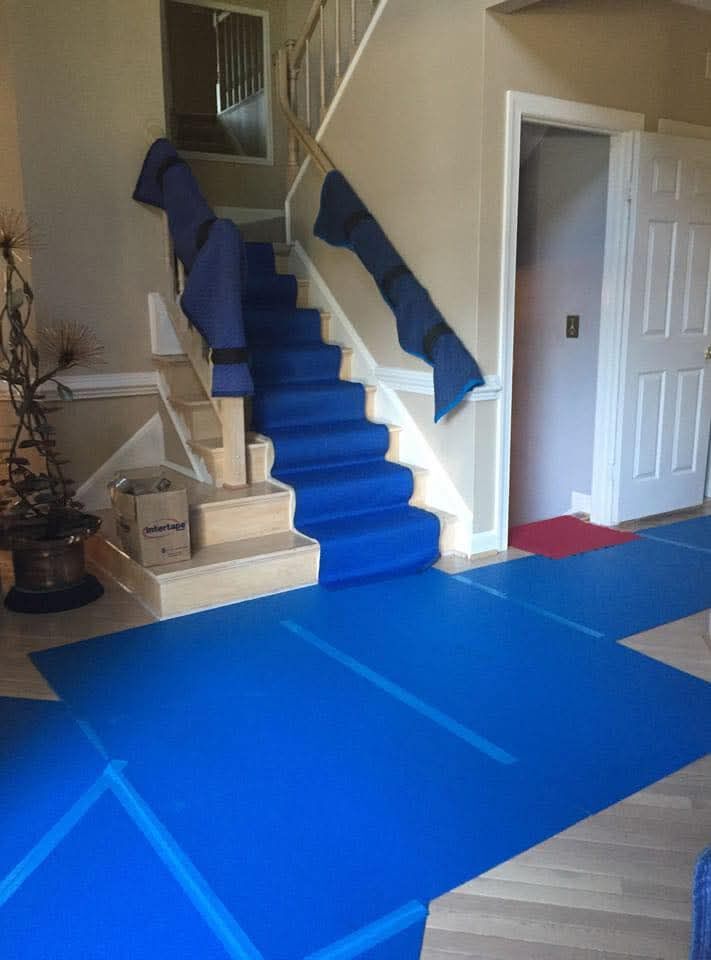 Residential staircase and entry floor fully protected with blue carpet runners and moving blanket pads on move day — One World Van Lines Lewisville, TX DFW Metroplex movers